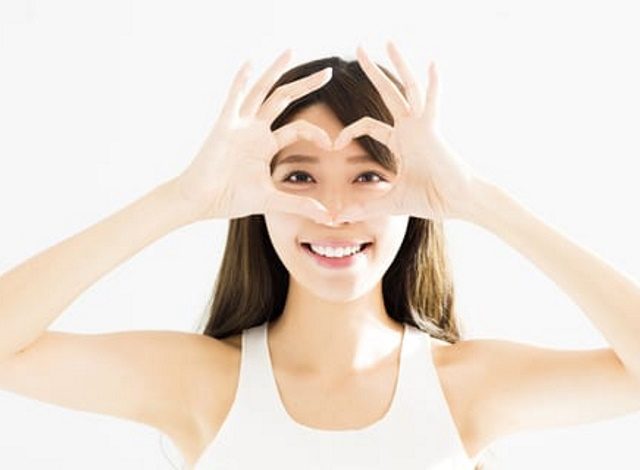 woman holding up hands in a heart shape